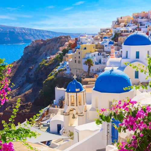 The stunning blue sea and bright white houses and churches with blue rooftops that make the Aegean Island of Santorini in Greece famous, and that can be toured on a vacation with Sky Bird Travel & Tours Sky Vacations.